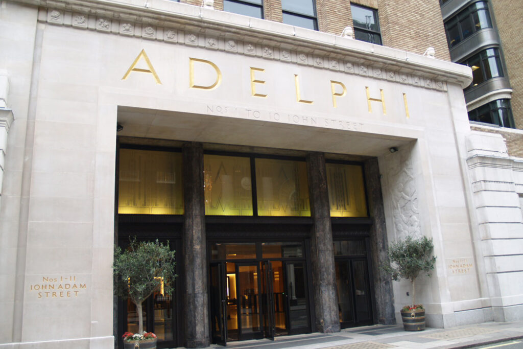 Styles Façade Solutions® delivers a bright, restored stone entrance at The Adelphi, showcasing the gold lettering and carved detailing against pale Portland stone. This finished view highlights the crisp architectural finish achieved across the building's main entrance, completing the extensive cleaning and restoration project.