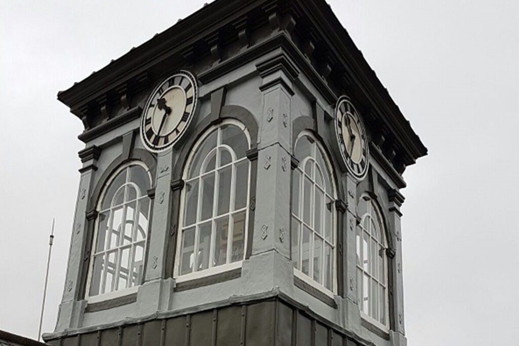 Styles Façade Solutions® delivers a flawless restoration of The Three Guineas clock tower, transforming peeling, weathered stonework into crisp grey and white paintwork. This finished view showcases the precision, quality, and lasting value Styles Façade Solutions® brings to heritage building restoration and redecoration projects.
