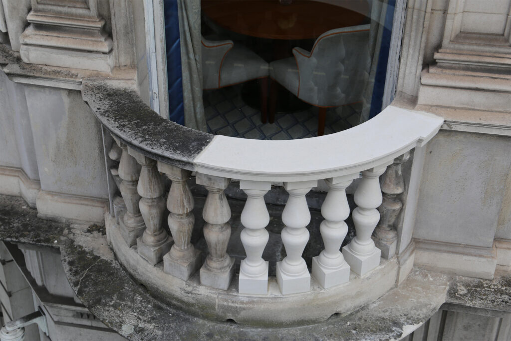 Styles Façade Solutions® completed this balcony restoration, replacing deteriorated balusters and handrail sections with precisely matched new stonework. The close-up reveals a seamless transition between original weathered stone and freshly restored elements, showcasing meticulous craftsmanship in heritage building conservation.
