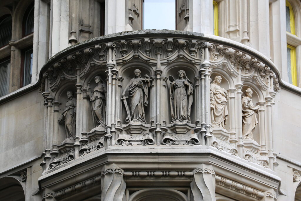 Styles Façade Solutions® restoring the ornate Portland stone façade of 13–15 Moorgate, London, using the Façade Gommage cleaning process. The treatment reveals the exceptional carved detail of the allegorical figures representing Justice, Truth, Prudence and other virtues, set within the building's distinctive curved Gothic-arched oriel bay.