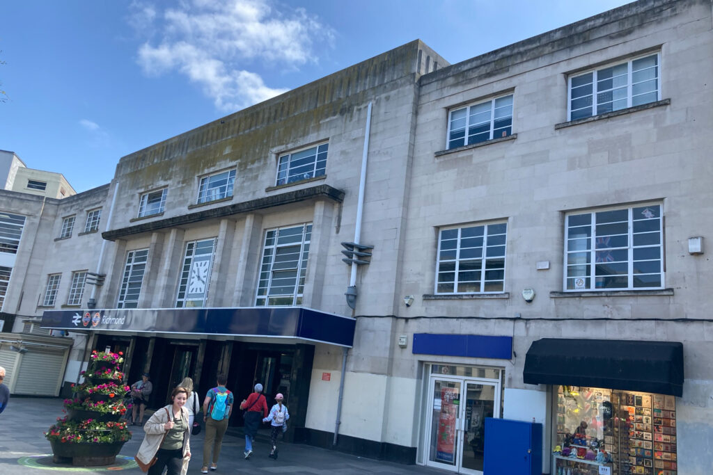 Styles Façade Solutions (formerly Thomann-Hanry®) was commissioned to survey, clean, and restore the Art Deco Portland stone façade of Richmond Station, London. This image shows the 1930s station building prior to treatment, with significant atmospheric soiling, biological growth and uneven discolouration clearly visible across the stone elevation and upper parapet.