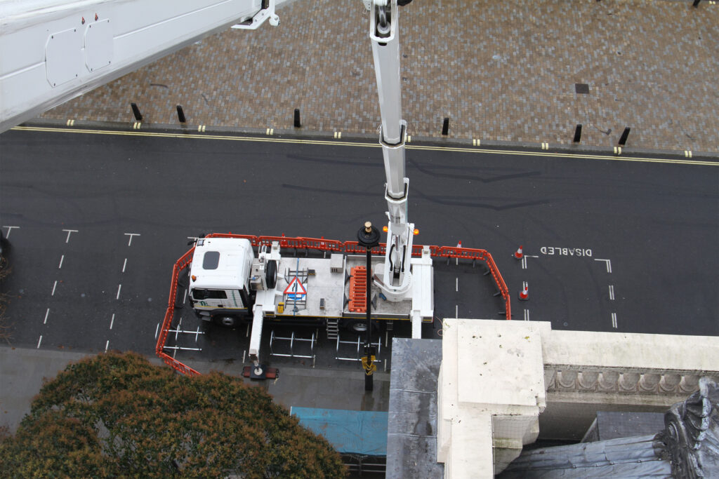 Styles Façade Solutions® deploys a truck-mounted platform with a fully certified, trained IPAF operator, seen from above extending its boom skyward on a cordoned London street.