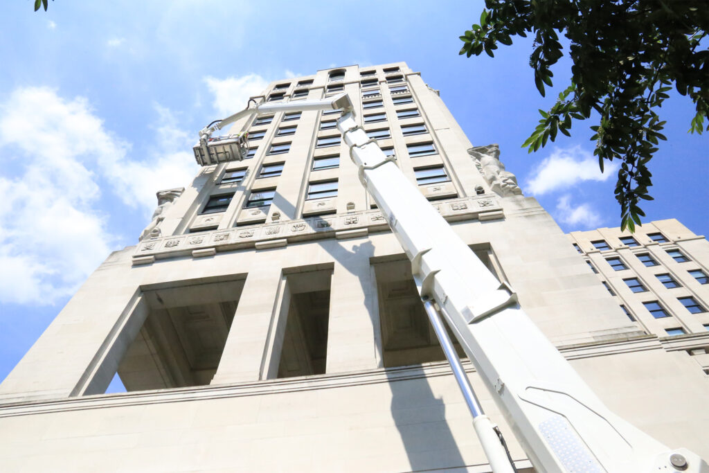 Styles Façade Solutions® conducting a scaffold-free façade survey of the Adelphi Building, London. A cherry-picker platform reaches the upper storeys to inspect the Art Deco stonework and carved reliefs, providing efficient, low-impact access for detailed condition assessment.