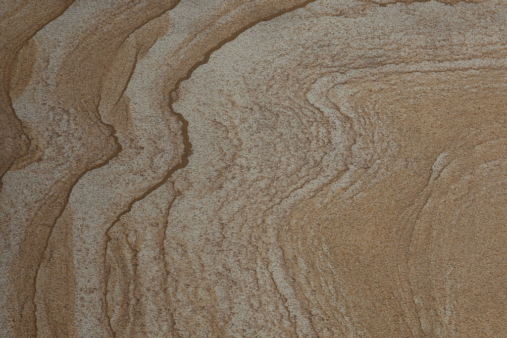 Styles Façade Solutions® showcases sandstone, a striking natural stone among the most visually distinctive façade materials. Its flowing bands of tan and grey create a dramatic, textured finish, ideal for commercial buildings and heritage properties seeking a bold, characterful natural stone appearance.